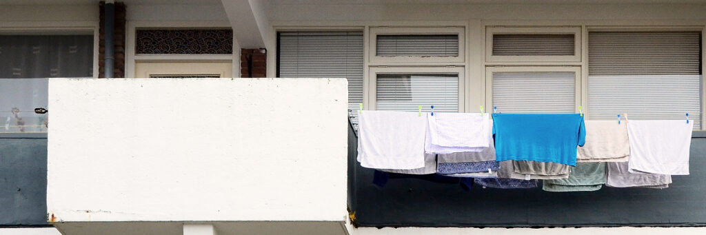 Balkon van een appartement met schone was aan een waslijn met wasknijpers