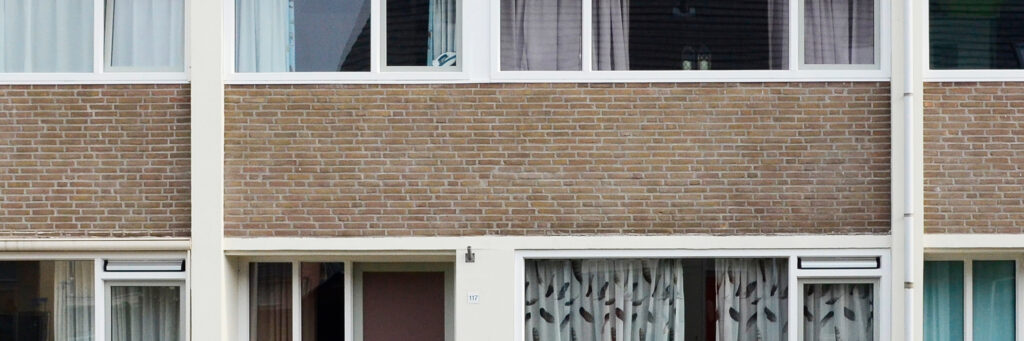 Woning met bruine bakstenen gevel en witte kozijnen