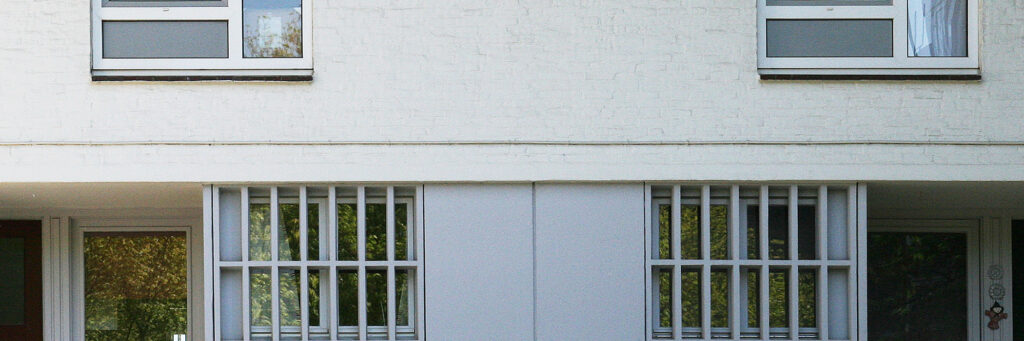 Woning met een witte bakstenen muur en tralies voor de ramen