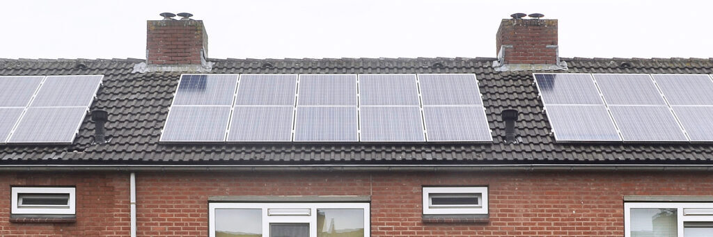 Eengezinswoning met zonnepanelen op het dak met bruine bakstenen muur en witte kozijnen