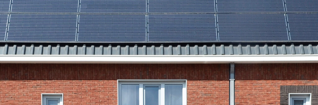 Eengezinswoning met zonnepanelen op het dak met bruine bakstenen muur en witte kozijnen