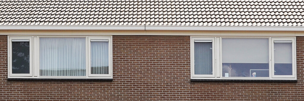 Eengezinswoning bovenverdieping en dak met bruine bakstenen muur en witte kozijnen