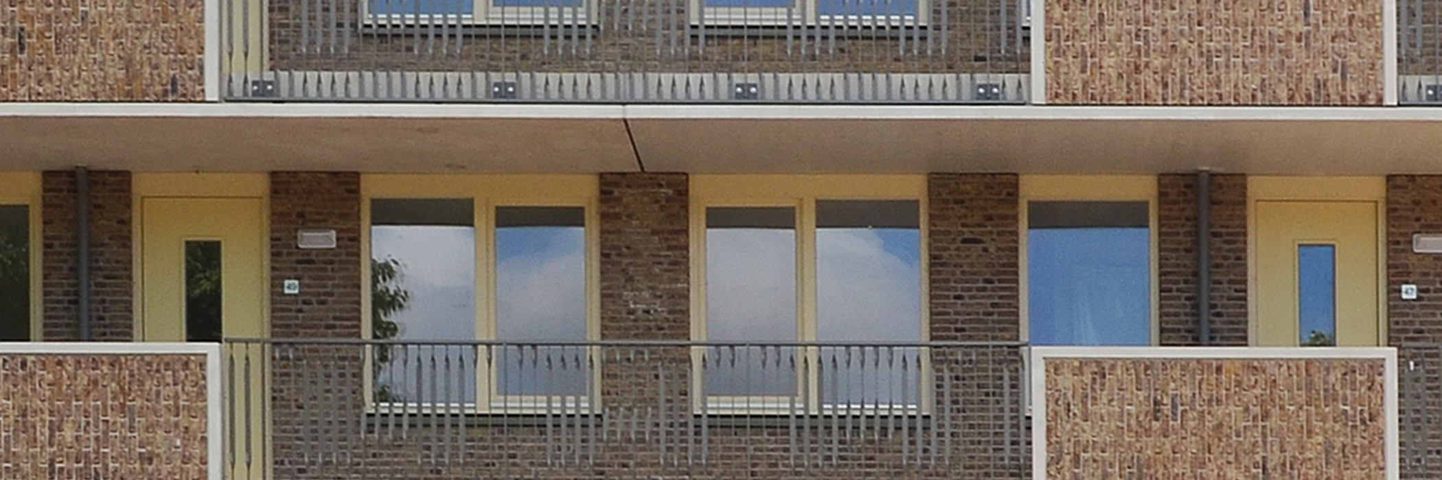Appartementencomplex met balustrade en gele kozijnen en deuren
