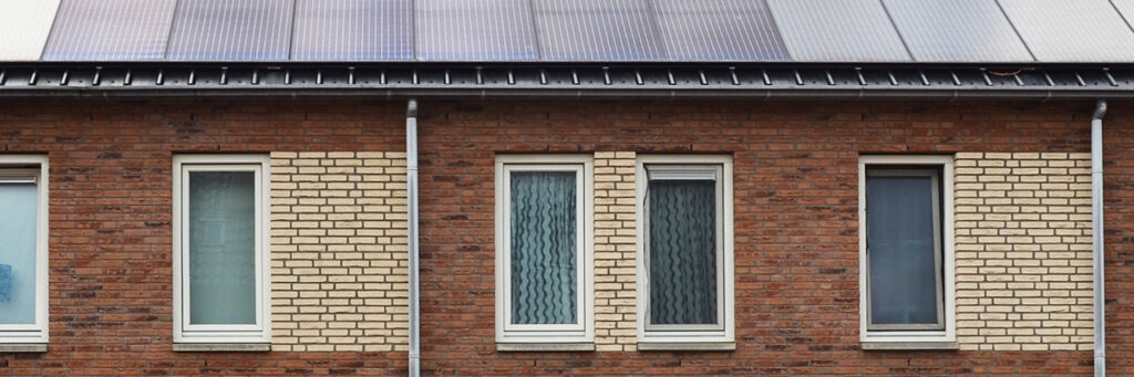 Eengezinswoning met zonnepanelen op het dak met bruine en beige bakstenen muur en witte kozijnen