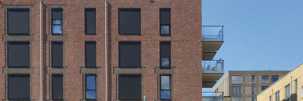 Appartementencomplex met balkons, bruine bakstenen muur en zwarte kozijnen