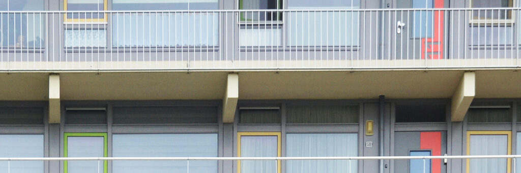 Appartementencomplex met een witte balustrade en gele deuren