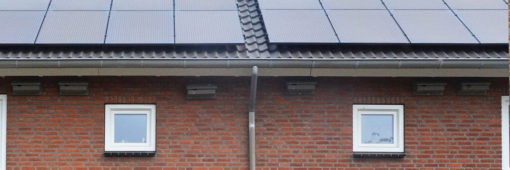 Eengezinswoning met zonnepanelen op het dak met bruine bakstenen muur en witte kozijnen