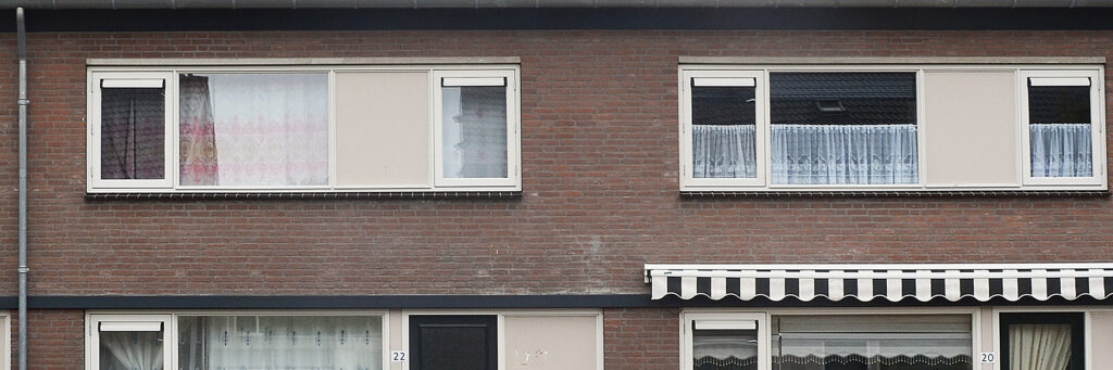 Eengezinswoningen met bruine bakstenen muur en crème kozijnen met een zonnenluifel