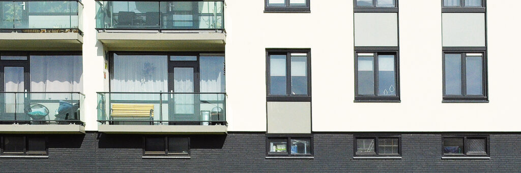 Appartementencomplex met balkons, een witte gevel en bruine kozijnen
