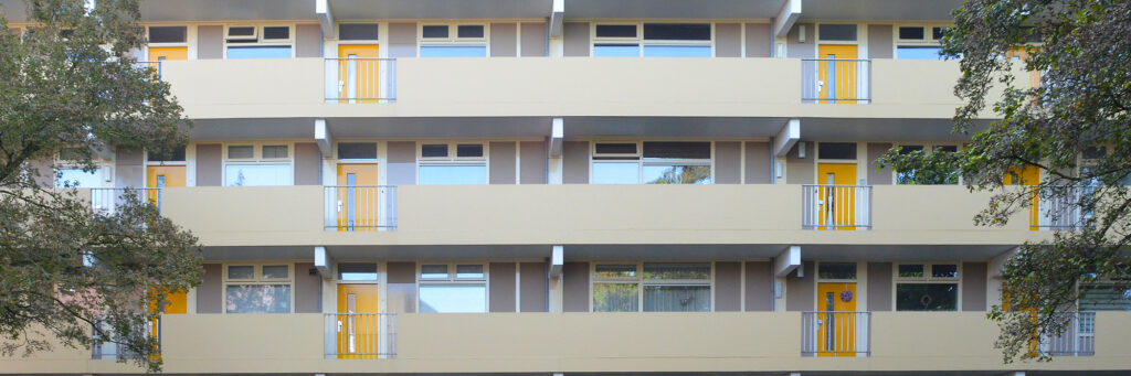 Appartementencomplex met een crème gevel en gele deuren