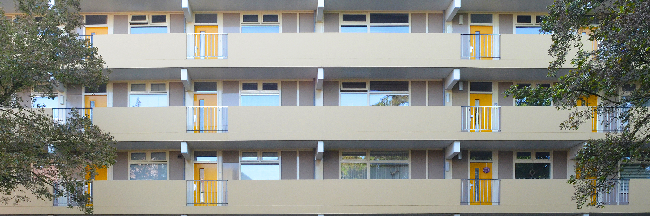 Appartementencomplex met een crème gevel en gele deuren