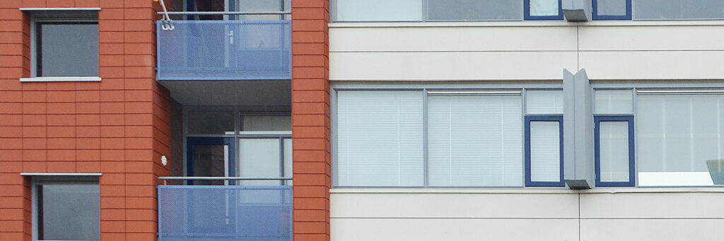 Appartementencomplex met een bruine bakstenen muur en een witte geven met blauwe balkon balustrades