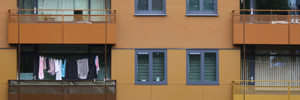 Appartementencomplex met een bruine gevel, blauwe kozijnen en schone was op het balkon