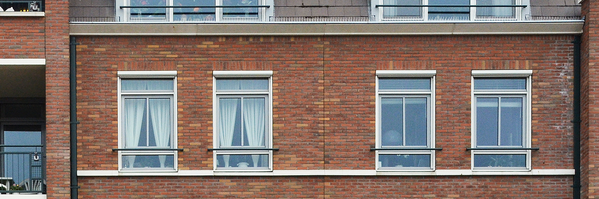 Appartementencomplex met bruine bakstenen muur en witte kozijnen