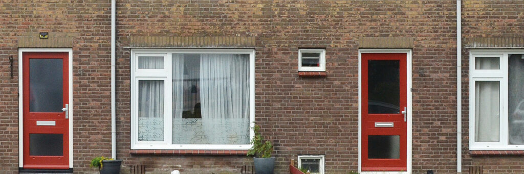 Woningen met rode deuren, witte kozijnen en een bakstenen muur