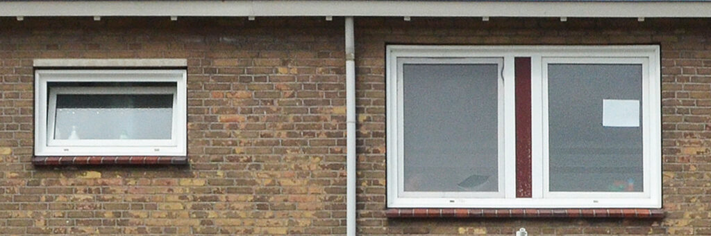 Bovenverdieping van een woning met witte kozijnen en een bakstenen muur