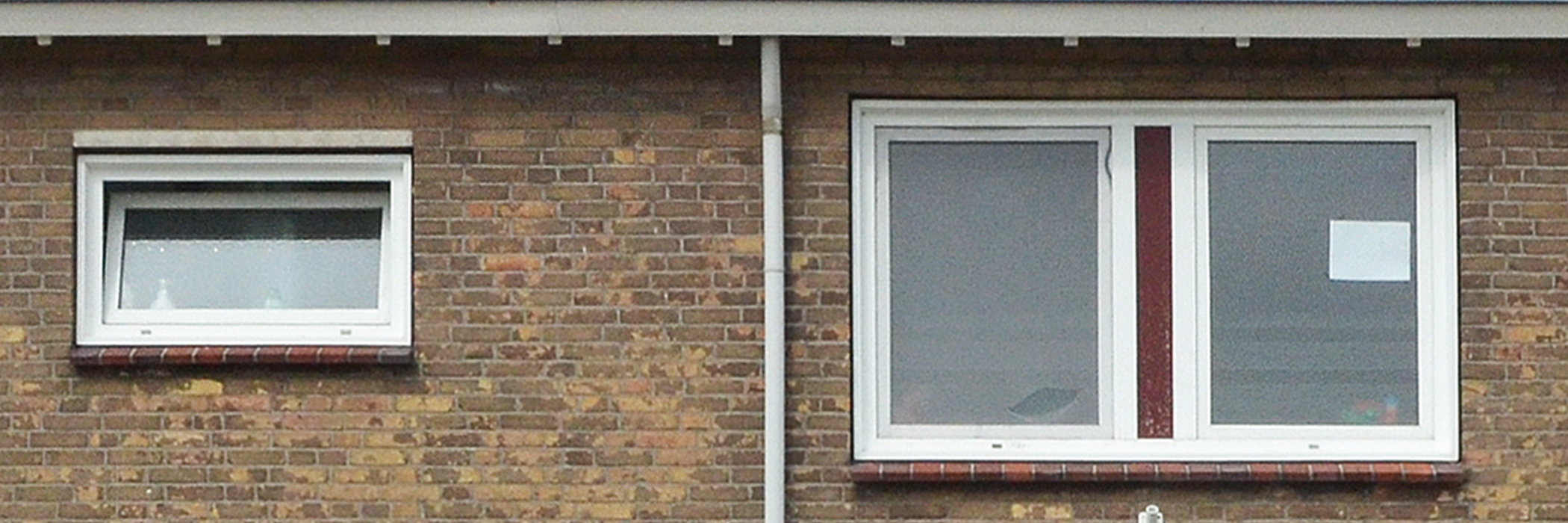 Bovenverdieping van een woning met witte kozijnen en een bakstenen muur