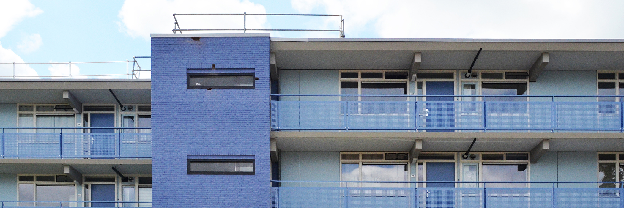 Appartementencomplex met een blauwe bakstenen gevel, witte kozijnen en blauwe balustrade