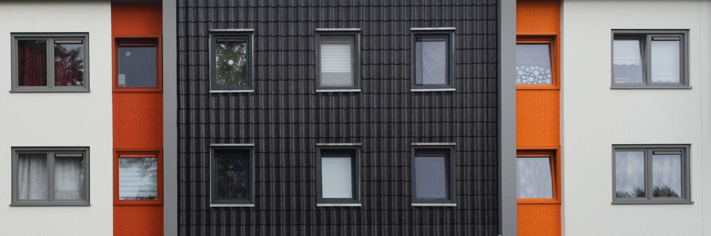 Appartementencomplex met een witte, oranje en zwarte gevel met grijze kozijnen