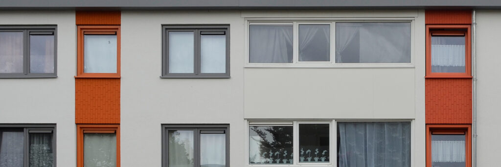 Appartementencomplex met een witte, oranje en zwarte gevel met grijze kozijnen