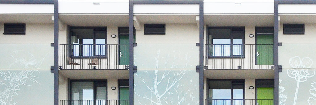 Appartementencomplex met witte muur, groene deuren en grijze balustrade