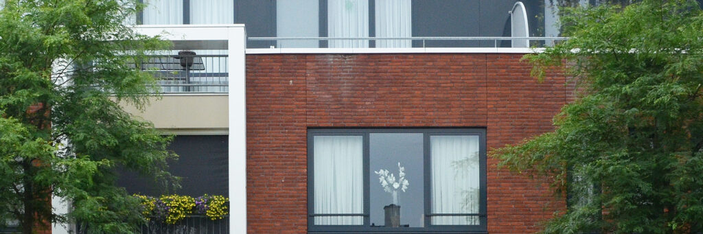 Appartementencomplex met donker rode bakstenen muur en grijze kozijnen