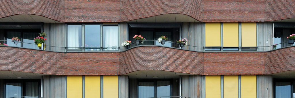Appartementen met balkons, bruine bakstenen muur en gele gevels