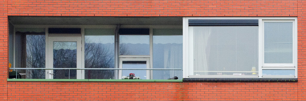 Appartement met rode bakstenen gevel, witte kozijnen en groene balustrade