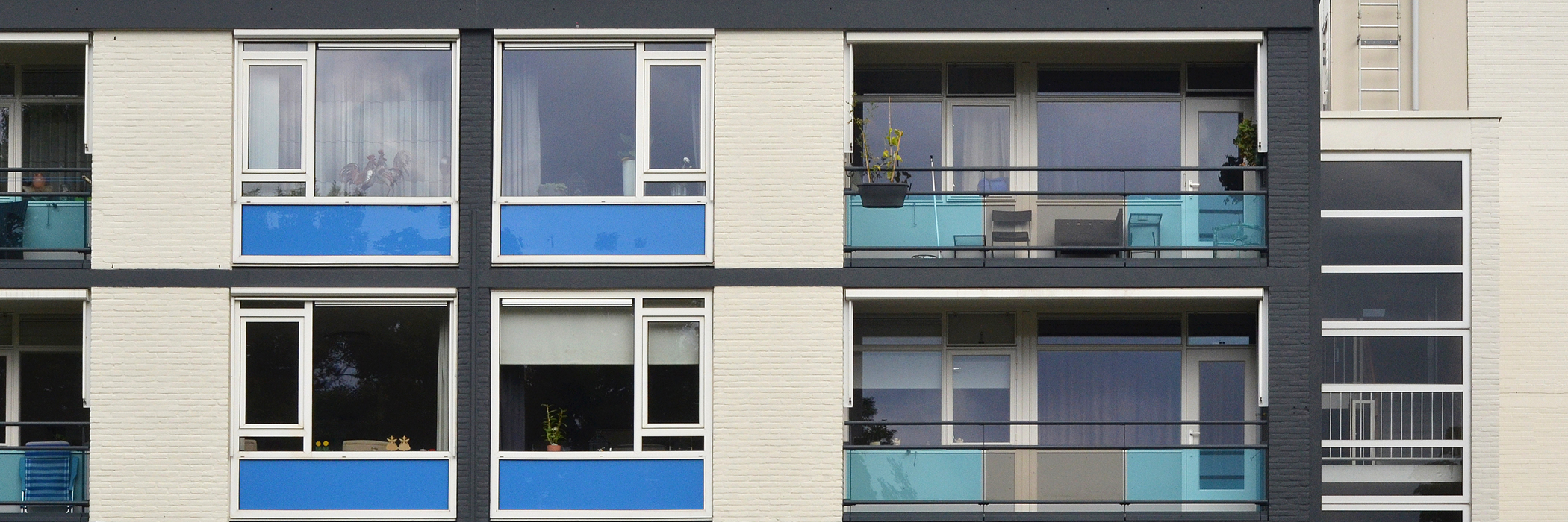 Appartementencomplex met een witte gevel, met witte kozijnen met blauwe platen