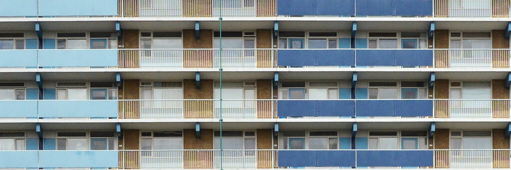 Appartementencomplex met lichtbruine bakstenen gevel, witte kozijnen, witte balustrade met licht en donkerblauwe balustrade platen