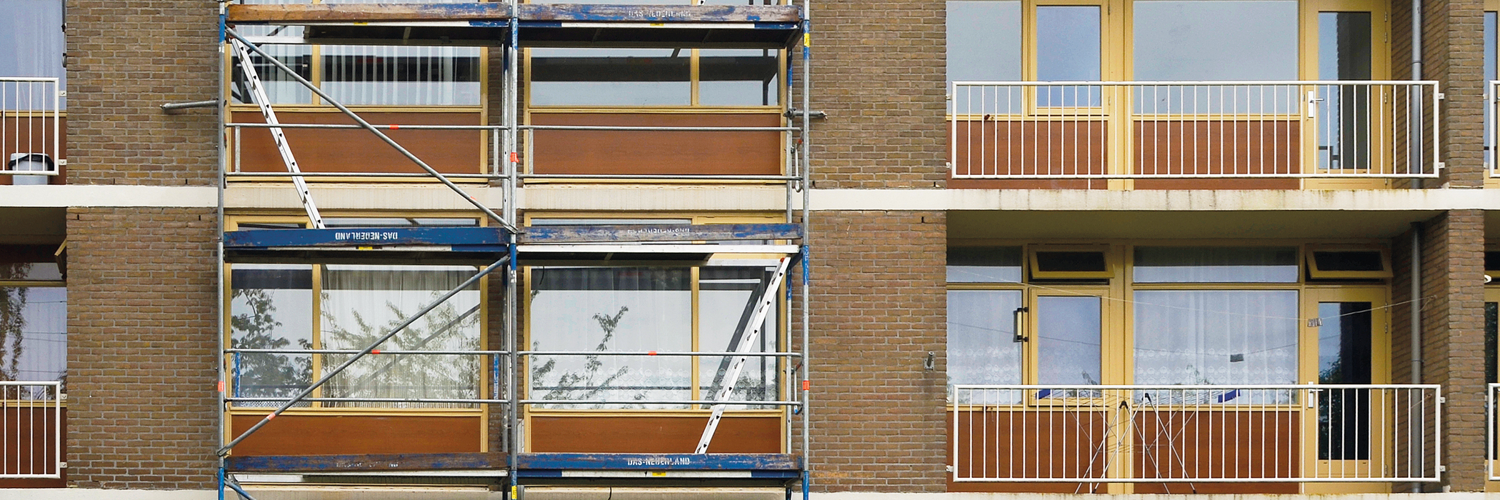 Appartementencomplex met bruine bakstenen muur, gele deuren en stijgers voor het complex
