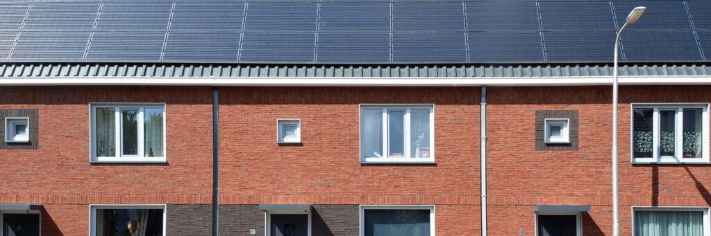 Woningen met bruine bakstenen muren, witte kozijnen en dak vol met zonnepanelen