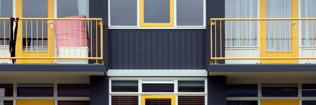 Appartementencomplex met zwarte gevel, witte kozijnen, gele deuren en balustrades