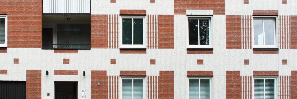 Appartementencomplex met een bruin witte bakstenen geven met witte kozijnen