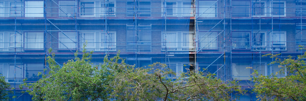 Appartementencomplex met stijgers voor het complex met blauwe doeken en bomen