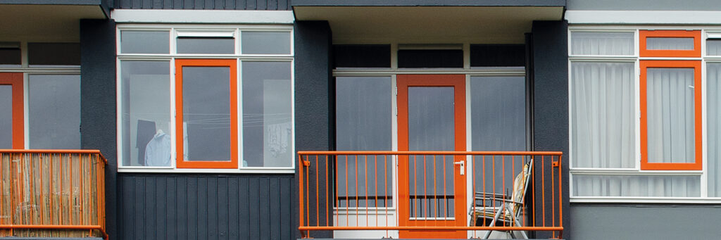 Appartementen met zwarte bakstenen gevel met witte kozijnen, oranje deuren en balustrade