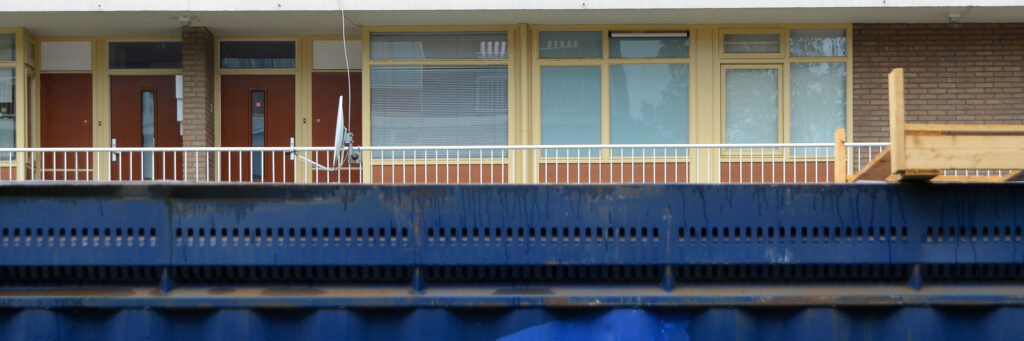Appartementencomplex met gele kozijnen, rode deuren en blauwe balustrade