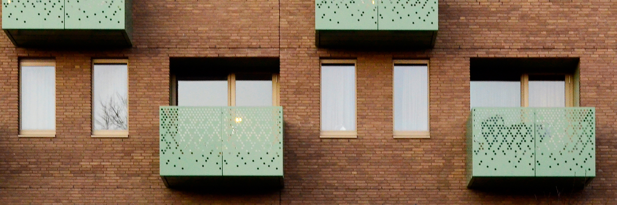 Appartementencomplex met bruine bakstenen muur en groene balkons