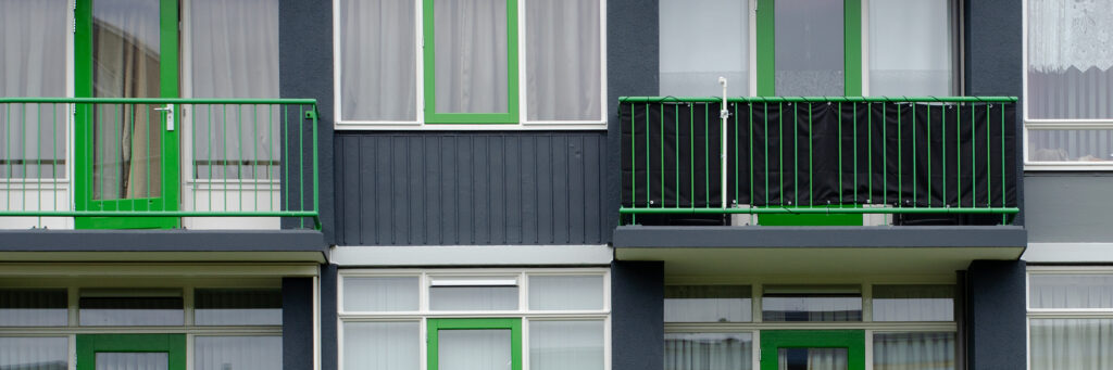 Appartementencomplex met zwarte gevel, witte kozijnen met groene balustrade