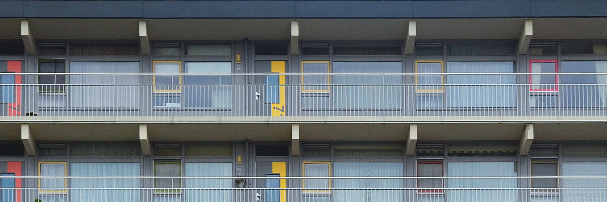 Appartementencomplex met grijze gevel, gele deur en grijze kozijnen