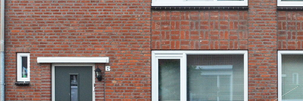Woning met bruine bakstenen gevel, witte kozijnen en grijze deur