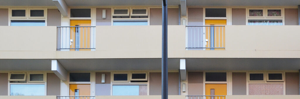 Appartementencomplex met crème gevel, crème balustrade en gele deuren