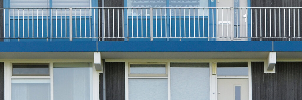 Appartementencomplex met zwarte gevel, witte kozijnen en blauwe balustrade