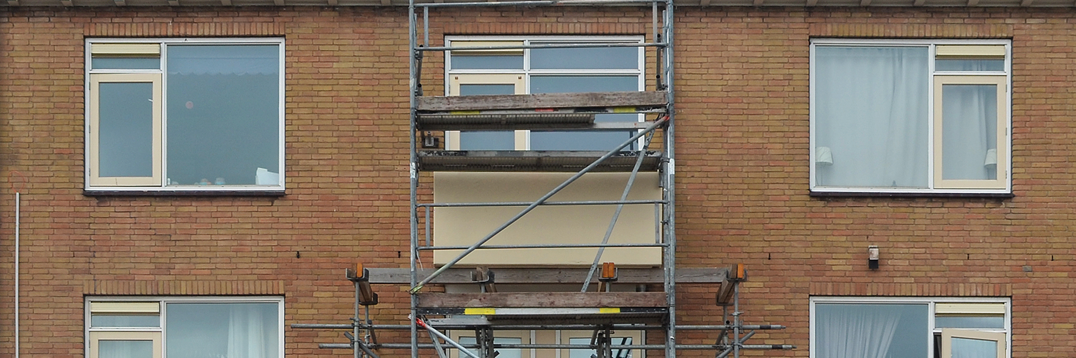 Appartementen met bruine bakstenen gevel, witte kozijnen en een stijger voor de deur
