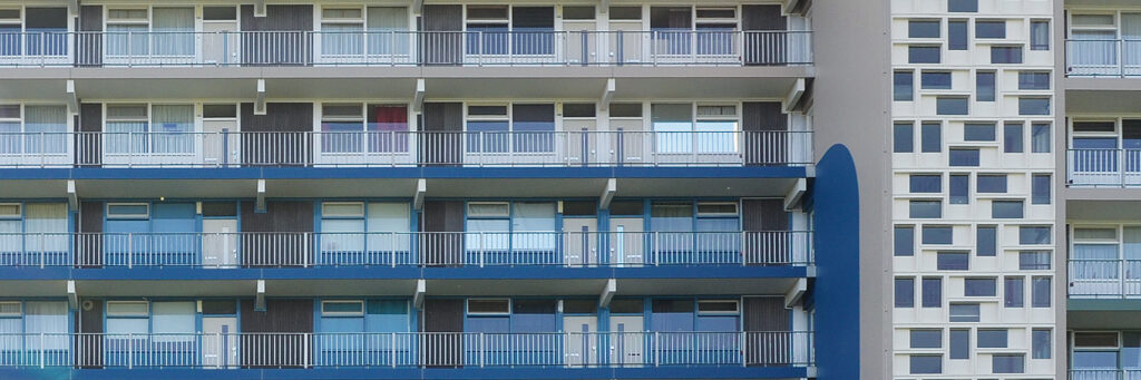 Appartementencomplex met bruine bakstenen gevel, witte kozijnen, blauwe balustrade en een witte gevel met blauwe vakken