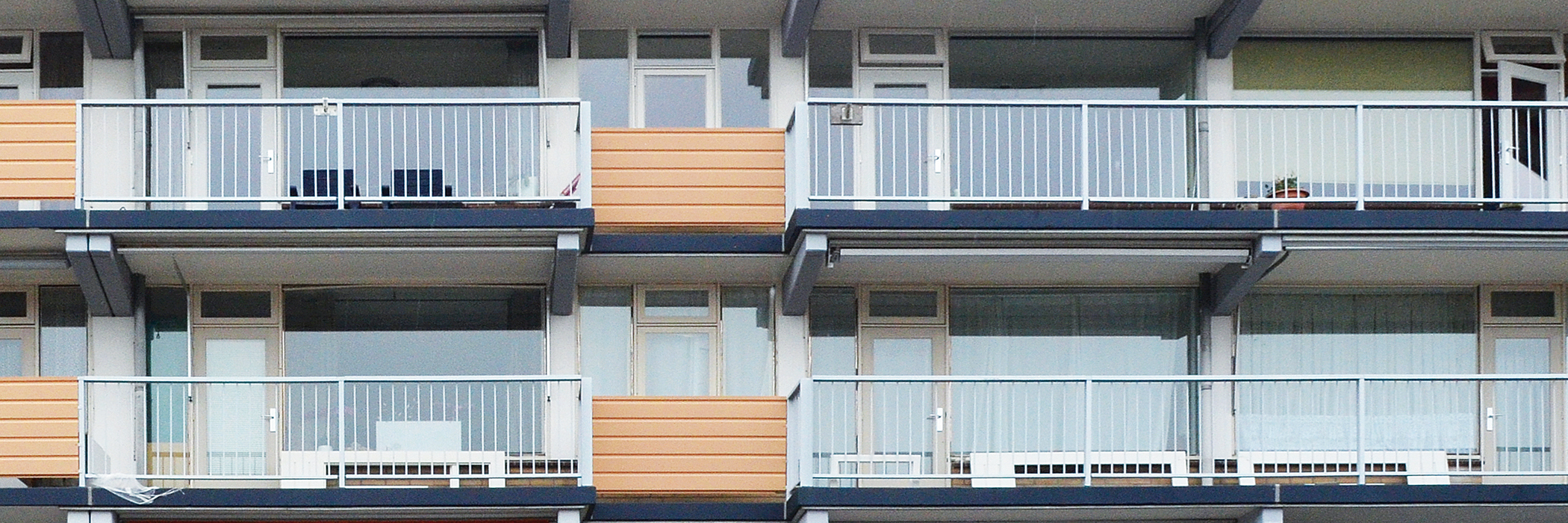 Appartementencomplex met witte kozijnen, bruine platen en grijze balustrade