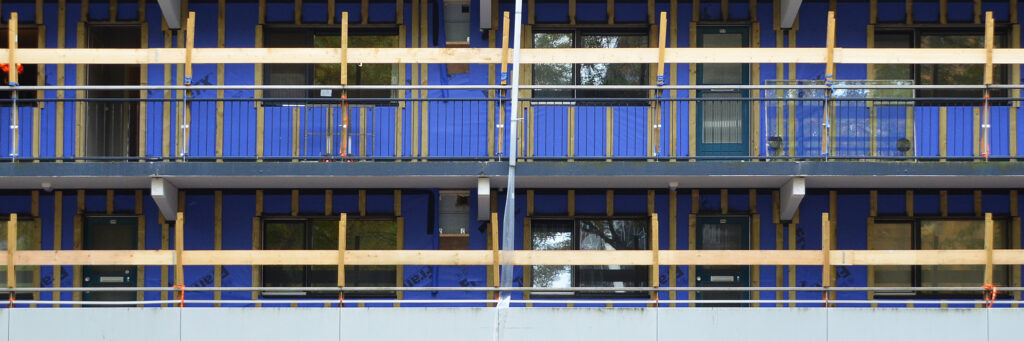 Appartementencomplex met blauwe platen en houten balkoen