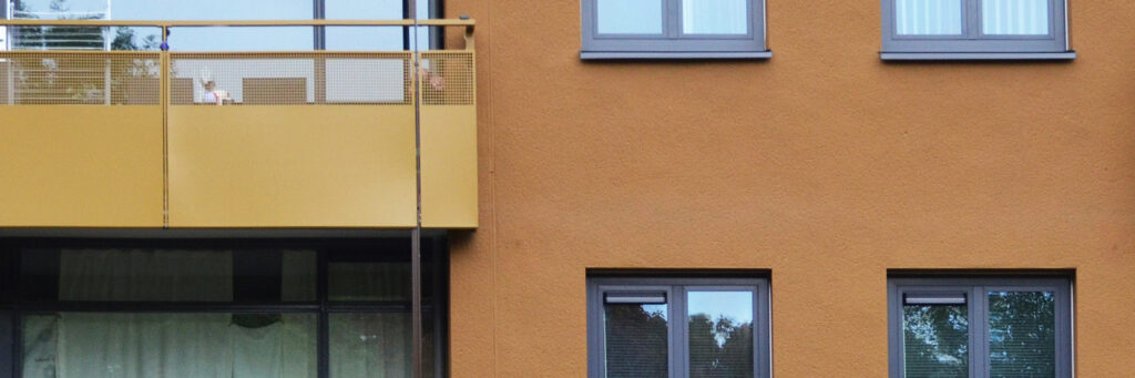 Appartementencomplex met bruine bakstenen gevel, grijze kozijnen en oranje balkon balustrade