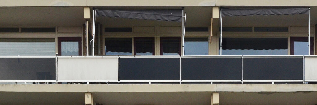 Appartementencomplex met crème gevel, grijze balkon balustrade met witte en zwarte vlakken