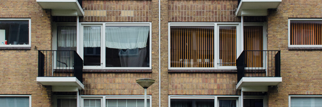 Appartementencomplex met bruine bakstenen gevel, witte kozijnen, zwarte balustrades en straatverlichting